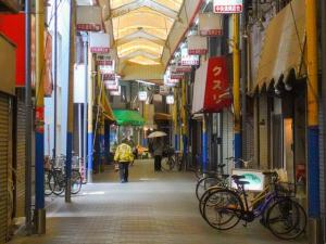 una persona caminando por un callejón con bicicletas en una calle en 鯉 en Osaka