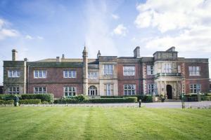 a large brick building with a lawn in front of it at De Vere Cranage Estate in Holmes Chapel