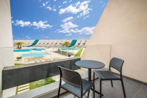 einen Balkon mit einem Tisch, Stühlen und einem Pool in der Unterkunft Occidental Mar Menor in Cartagena