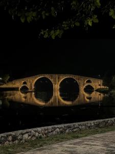 uma ponte de pedra à noite com o seu reflexo na água em Apartmani HM em Trebinje