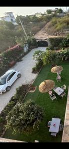 a white car parked in a yard with tables and umbrellas at Zarafah in Poponguine