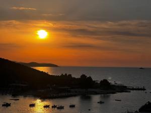 una puesta de sol sobre un cuerpo de agua con barcos en Dine Apartments, en Ksamil