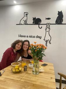 dos mujeres sentadas en una mesa con gatos en la pared en Easy House en Zhangjiajie