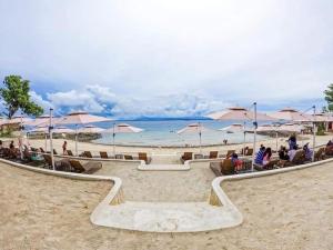 a group of people sitting on a beach with umbrellas at Mactan Newtown Beach Condo in Mactan