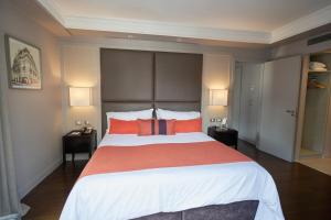 1 dormitorio con 1 cama grande con almohadas de color naranja en Carles Hotel en Buenos Aires