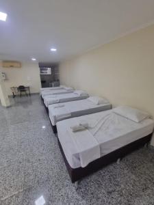 uma fila de camas alinhadas num quarto em Pousada e Hospedaria Regina em Cachoeiro de Itapemirim