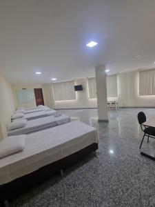 um quarto com quatro camas e uma mesa e cadeiras em Pousada e Hospedaria Regina em Cachoeiro de Itapemirim