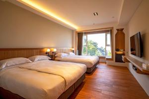 a hotel room with three beds and a television at Hotel Woodland in Tongxiao