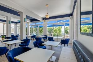 a restaurant with tables and chairs and large windows at Hotel Espadon bleu in Le Lavandou