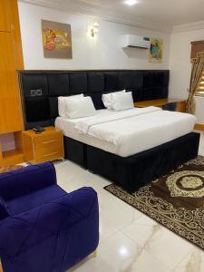 1 dormitorio con 1 cama grande y 2 sillas moradas en Kawruky Hotel Benin en Benin City