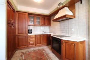 a kitchen with wooden cabinets and a black dishwasher at Apartment Frketić with roof terrace and panoramic sea view in Opatija