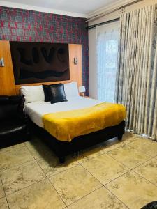 sypialnia z dużym łóżkiem i żółtym kocem w obiekcie Parow city -Andrienna Lodge w Kapsztadzie