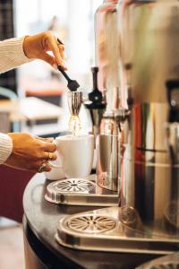 Eine Frau rührt eine Tasse Kaffee in einer Kaffeemaschine. in der Unterkunft Stay Hotel Lisboa Aeroporto in Lissabon