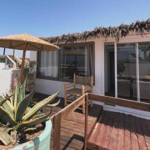 una terraza de madera con una silla y una sombrilla en Surf HouseMaroc en Esauira