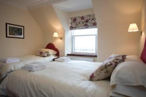 two twin beds in a room with a window at The Ship Inn in Stonehaven