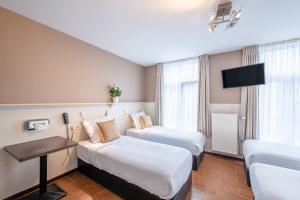 a hotel room with two beds and a couch at Hotel Barry in Brussels