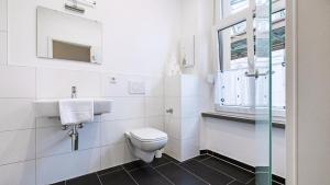 a bathroom with a toilet and a sink and a window at Hotel Schwaferts in Wuppertal