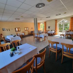 uma sala de jantar com mesas brancas e cadeiras de madeira em Hotel Apfelblüte em Wendorf