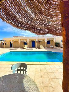 einen Pool mit einem Tisch und einem Sonnenschirm in der Unterkunft Dar Melody in Djerba