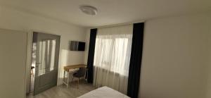 a bedroom with a bed and a window and a desk at Alex House in Făgăraş