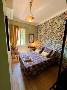 a bedroom with a bed with a floral wallpaper at Hotel Le Ponteil in Antibes