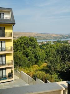 um edifício de apartamentos amarelo com varanda e árvores em Adam Home Ap em Falticeni