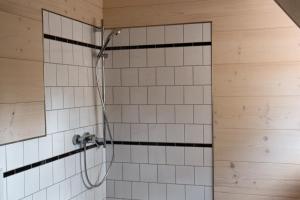 a shower in a bathroom with white tiles at Apartmán 121 in Nové Město na Moravě