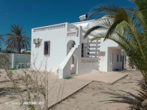 a white house on the beach with a palm tree at La rose 1 in Mezraya