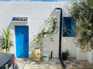 a white building with a blue door and a plant at Le Refuge Djerbien in Houmt Souk