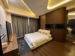 um quarto com uma cama e uma televisão de ecrã plano em AEON SUITES STAYCATION managed by ARIA HOTEL em Davao