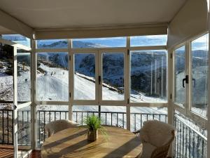 een kamer met een tafel en uitzicht op een besneeuwde berg bij Luxury Apartment Zona baja in Sierra Nevada