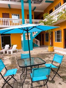 a table and chairs under a blue umbrella at Hotel y Restaurante Casa Jardines in San Benito