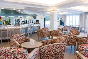 een restaurant met stoelen en tafels en een bar bij Hotel Voramar in Cala Millor