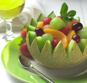 a bowl of fruit on a plate with a glass of wine at Hotel Arena Fes in Fez