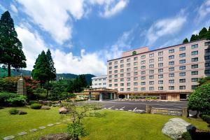 een groot gebouw met een parkeerplaats ervoor bij Kirishima Hotel in Kirishima