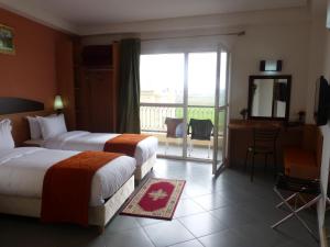 a hotel room with two beds and a balcony at Hotel Arena Fes in Fez