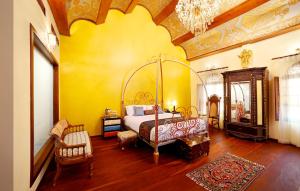 um quarto com uma cama e uma parede amarela em Ginger House Museum Hotel em Cochin