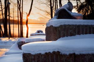 eine Reihe von Bänken mit Schnee bei Sonnenuntergang in der Unterkunft Hotel Hanasaari in Espoo