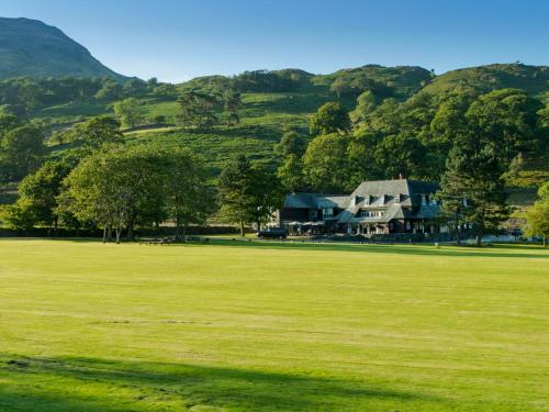 ein großes Grasfeld mit einem Haus in der Ferne in der Unterkunft Glaramara Hotel in Borrowdale Valley