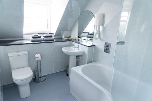 a white bathroom with a toilet and a sink at Leys Hotel in Aberdeen