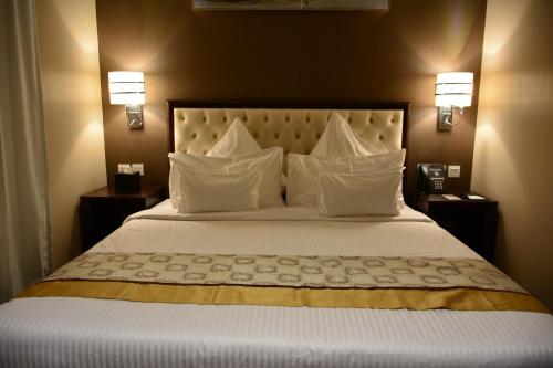 um quarto com uma cama grande e almofadas brancas em Home Inn Hotel Suites em Al Khobar