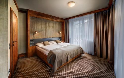 een slaapkamer met een bed en een groot raam bij Hotel Pošta in Demanovska Dolina