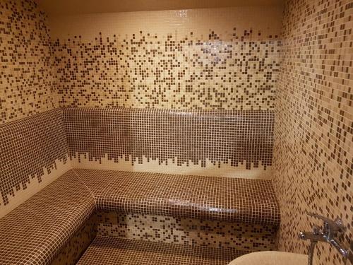 a tiled bathroom with a tub and a sink at Family Prim Hotel in Sandanski