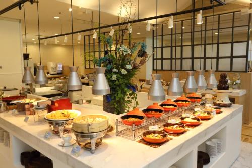 ein Buffet mit Schalen und Teller mit Speisen in der Unterkunft Loisir Hotel Toyohashi in Toyohashi