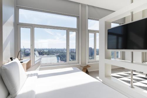 ein weißes Schlafzimmer mit einem großen Fenster und einem TV in der Unterkunft Hub Hotel Asuncion in Asunción