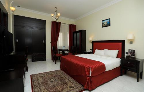 een slaapkamer met een bed met een rode deken en een tafel bij Remas Hotel Suites - Al Khoudh, Seeb, Muscat in Seeb