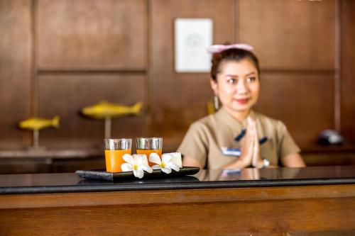 Eine Frau, die an einer Bar mit einem Tablett mit Getränken sitzt. in der Unterkunft Sea Valley Resort in Lipa Noi