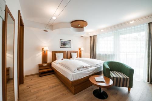 ein Hotelzimmer mit einem Bett und einem Stuhl in der Unterkunft KRONE eat drink stay in Brixen