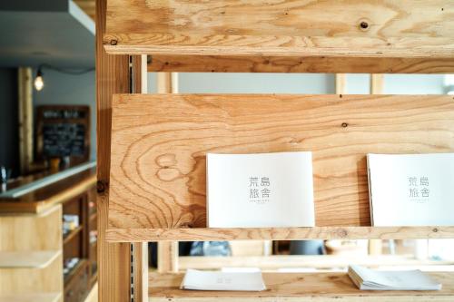 una estantería de madera con tres letreros blancos. en Arashima Hostel, en Ōno