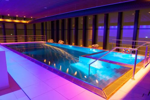 a large swimming pool in a building with purple lighting at Fletcher Wellness-Hotel Leiden in Leiden